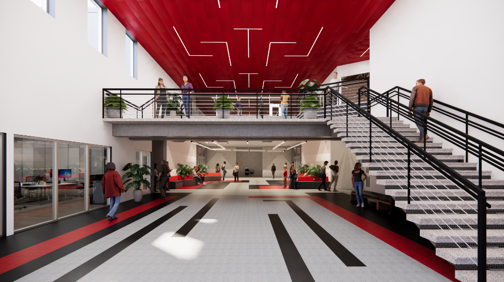 Spacious modern lobby with a red ceiling, black railings, plants, and people walking or talking; a staircase leads to a mezzanine level.
